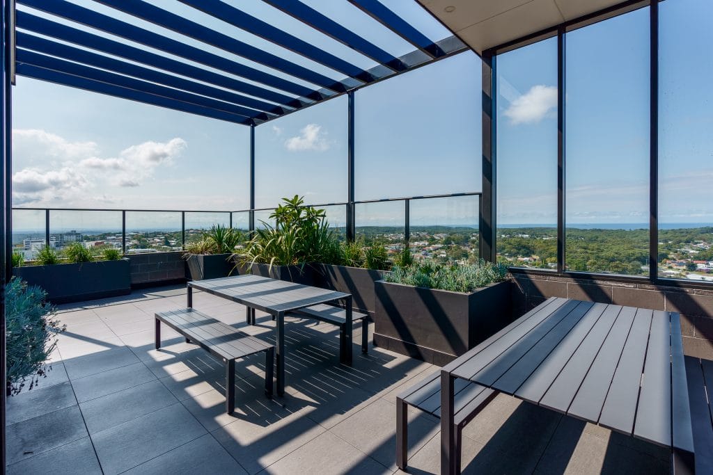 Rooftop terrace featuring modern seating, potted plants, and panoramic views of the landscape.